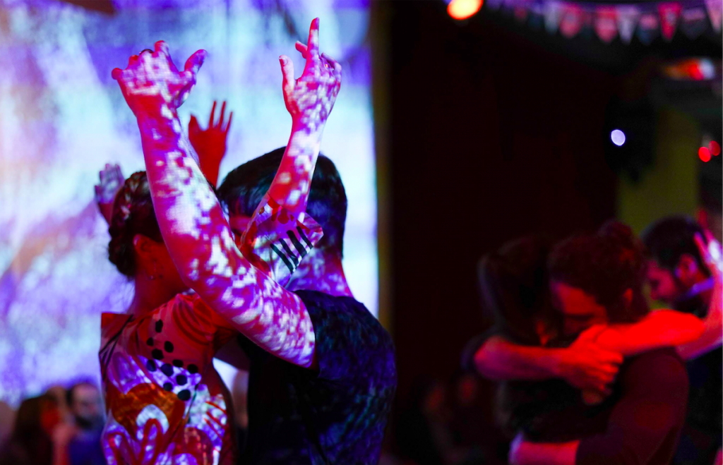 Die Berliner lieben den Tango: Ein Tanzpaar bei der Domilonga vor einer Wand mit einer Videoprojektion.